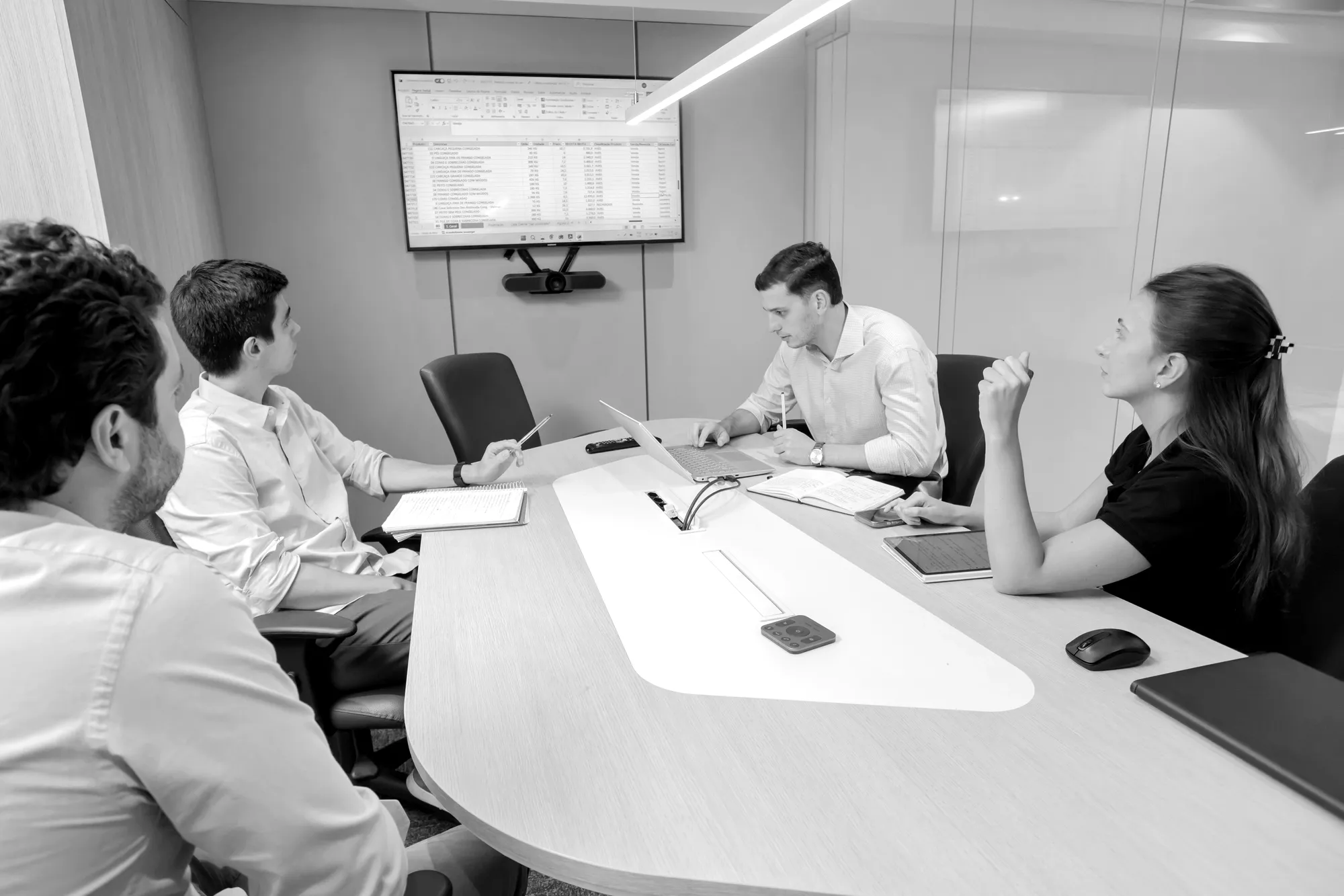 A team in a boardroom reviewing data on a wall screen
